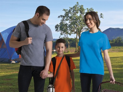 Família com t-shirts coloridas num parque com tenda e árvores ao fundo.