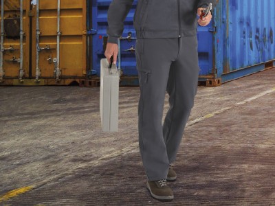 Pessoa com roupa de trabalho cinzenta e mala metálica prateada num espaço industrial