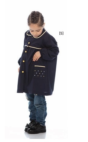 Criança com casaco azul escuro de botões dourados e bolso com detalhes em branco