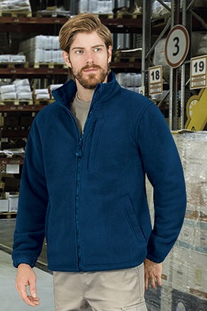 Homem com casaco polar azul escuro num armazém com prateleiras e placas numeradas no fundo