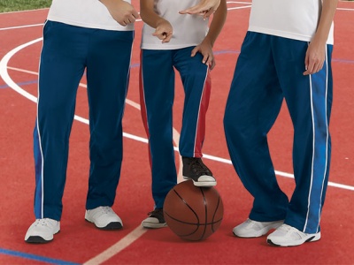Três pessoas com calças desportivas azuis com riscas laterais, pé numa bola de basquetebol numa pista desportiva