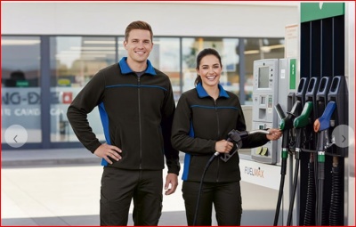 Duas pessoas com uniformes pretos e azuis numa estação de combustível FUELMAX