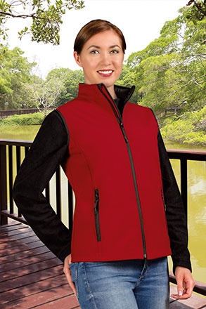 Colete vermelho com fecho preto usado por mulher em ambiente natural ao lado de lago