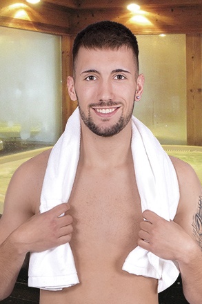 Homem jovem com toalha branca sobre os ombros num spa de madeira