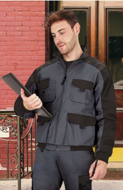 Homem com uniforme cinzento e preto segurando uma placa digital diante de parede de tijolos vermelhos