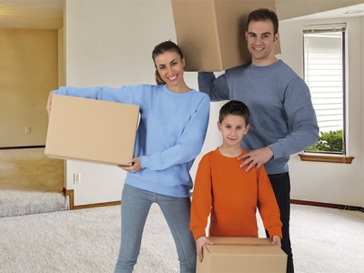 Família em casa segurando caixas de cartão, com camisolas azul claro, cinza e laranja.