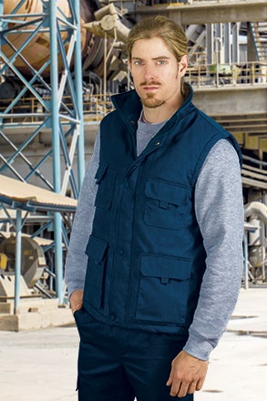 Homem com colete azul e t-shirt cinzenta em ambiente industrial