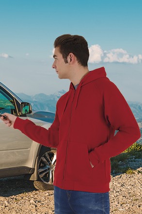Homem com hoodie vermelho junto a carro em ambiente montanhoso