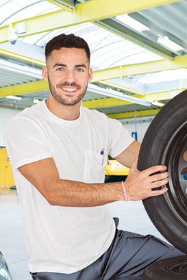 Homem segurando pneu automóvel num ambiente industrial