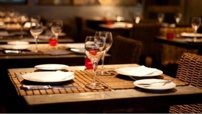 Mesa posta com pratos, copos e guardanapos em restaurante com iluminação quente