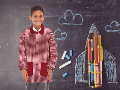 Criança com bata escolar vermelha xadrez e desenho de foguete no quadro negro