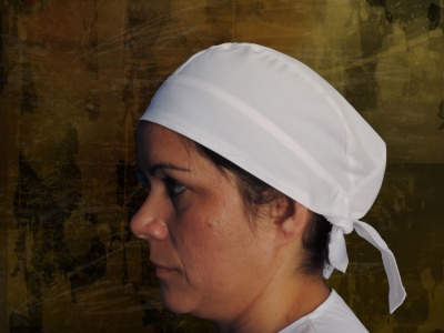 Pessoa com lenço branco amarrado na cabeça sobre fundo castanho