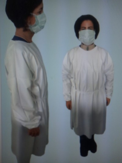 Dois modelos femininos com batas médicas brancas e máscaras contra fundo claro