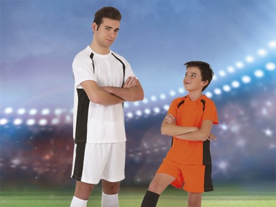 Dois rapazes em equipamento de futebol branco e laranja num campo iluminado