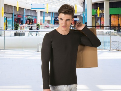 Homem jovem com camisa preta de manga comprida segurando saco de compras dourado em centro comercial