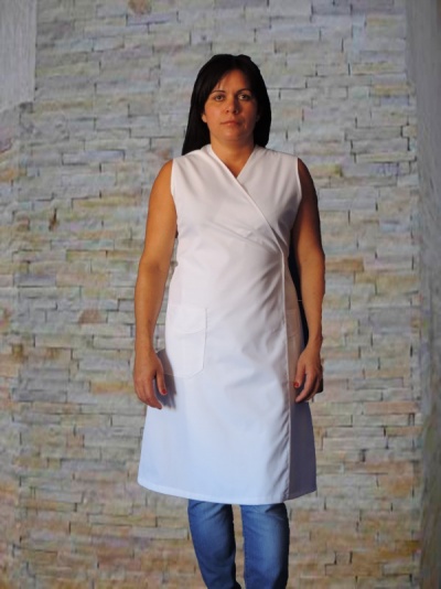 Vestido branco com bolso frontal usado por mulher em fundo de parede de pedra clara