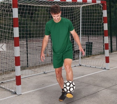 Homem a jogar futebol numa quadra com baliza de futsal