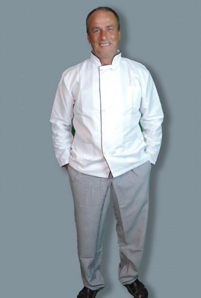 Homem com bata de chef branca e calças xadrez cinza em fundo cinzento.