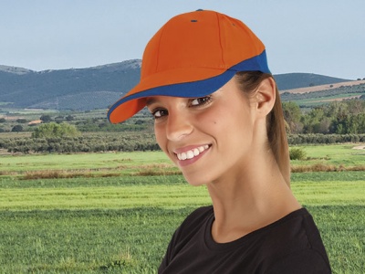 Mulher sorridente a usar boné laranja com aba azul no campo