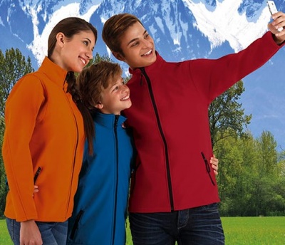 três pessoas com casacos fleece coloridos em cenário natural com montanhas e árvores