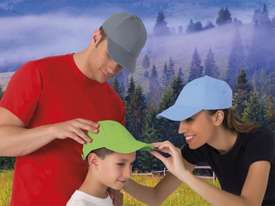 Três pessoas com t-shirts e bonés coloridos num ambiente natural com árvores e névoa