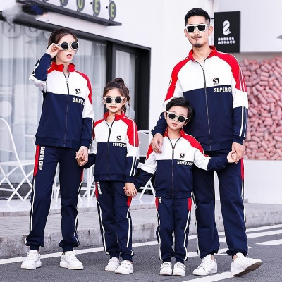 Família de quatro com fatos de treino azul escuro, vermelho e branco com texto 'SUPERB' e 'SUPERC' usando óculos de sol.