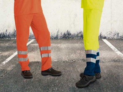 Pessoas vestindo pantalonas de trabalho com faixas refletoras em estacionamento