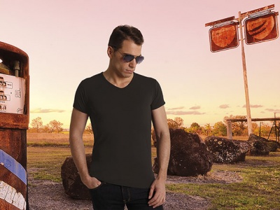 Homem com t-shirt preta e óculos de sol junto a bomba de gasolina antiga ao pôr do sol