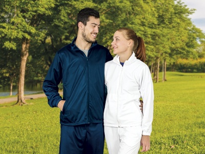 Casal em fatos de treino azul escuro e branco ao ar livre com árvores e relva