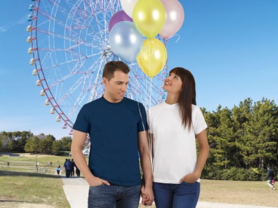Homem e mulher com t-shirts simples e balões coloridos num parque com roda gigante ao fundo