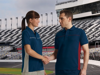 Casal a usar polos azul escuro com riscas e a cumprimentar-se num estádio desportivo