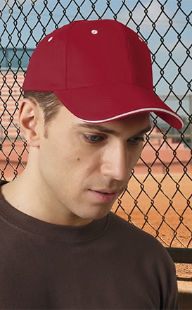 Boné desportivo vermelho com orifícios de ventilação brancos usado por homem junto a cerca de metal preta