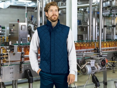 Homem com colete azul acolchoado em fábrica de produção