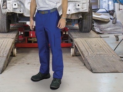 Homem com calças de trabalho azuis e sapatos de segurança pretos numa oficina automóvel