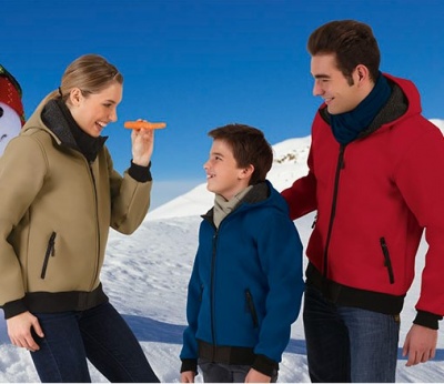 Três pessoas com casacos bege, azul e vermelho, ao ar livre na neve sob céu azul.