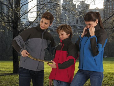 três pessoas com casacos de fleece a observar uma jibóia num parque urbano