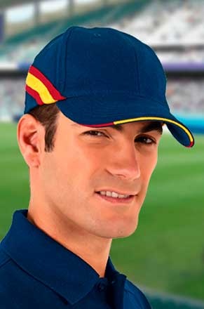 Homem com boné azul escuro com detalhes vermelho e amarelo em estádio desfocado