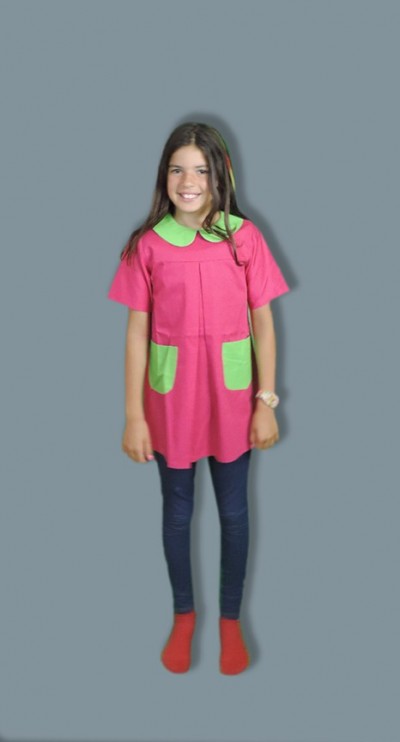 Menina com túnica rosa e verde, calças azuis escuras e meias vermelhas em fundo cinza