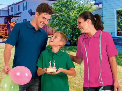 Três pessoas com camisolas tipo polo coloridas e bolo de aniversário no exterior