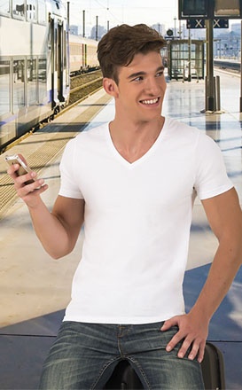 Homem jovem com t-shirt branca sentado numa estação de comboios