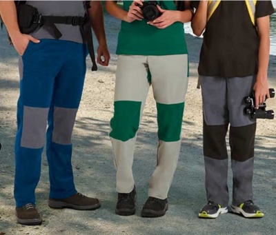 Três pares de calças reforçadas em várias cores num ambiente ao ar livre.