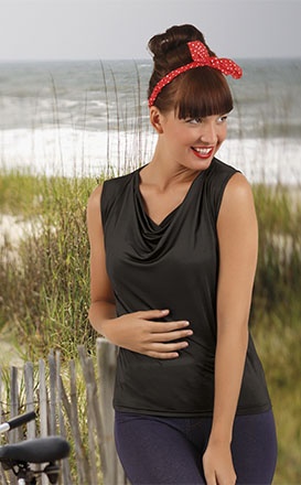 Mulher com blusa preta sem mangas e faixa vermelha com bolinhas no cabelo, em ambiente de praia
