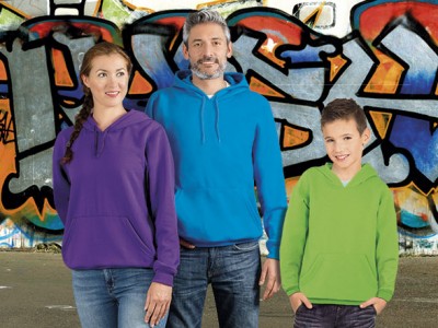 Três pessoas com sweatshirts coloridas em frente a parede grafitada