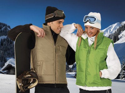 Dois homens e mulheres com coletes acolchoados em ambiente de neve com prancha de snowboard.