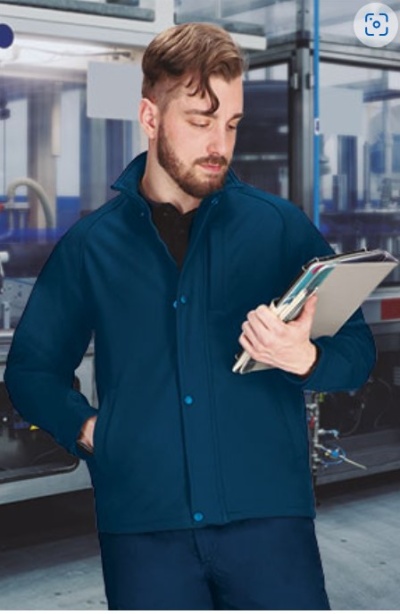 Homem com casaco azul escuro e camisa preta segurando cadernos em ambiente industrial