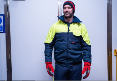 Homem com uniforme de proteção amarelo e azul escuro, luvas vermelhas e gorro preto com vermelho
