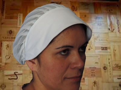 Touca de rede branca com faixa opaca usada por mulher em frente a parede com rótulos de vinho