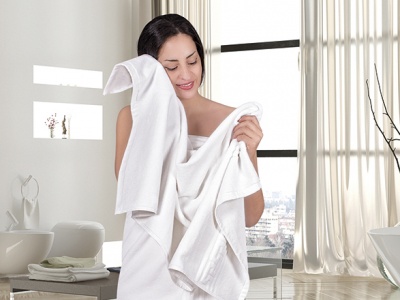 mulher a secar o rosto com toalha branca numa casa de banho moderna