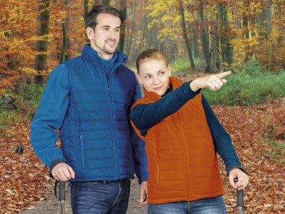 Casal com coletes acolchoados azul e laranja numa floresta de outono