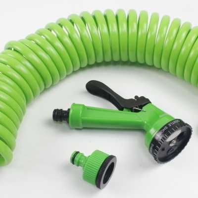 Manguera de jardim verde enrolada com esguicho e adaptadores em fundo branco